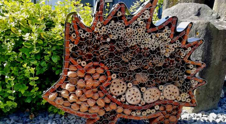 Insektenhotel in Form eines Igels aus Holz mit verschiedenen Röhren und Löchern